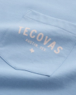 Close-up of a light blue shirt pocket with the words "TECOVAS AUSTIN, TEX." and a small Texas outline printed in white.