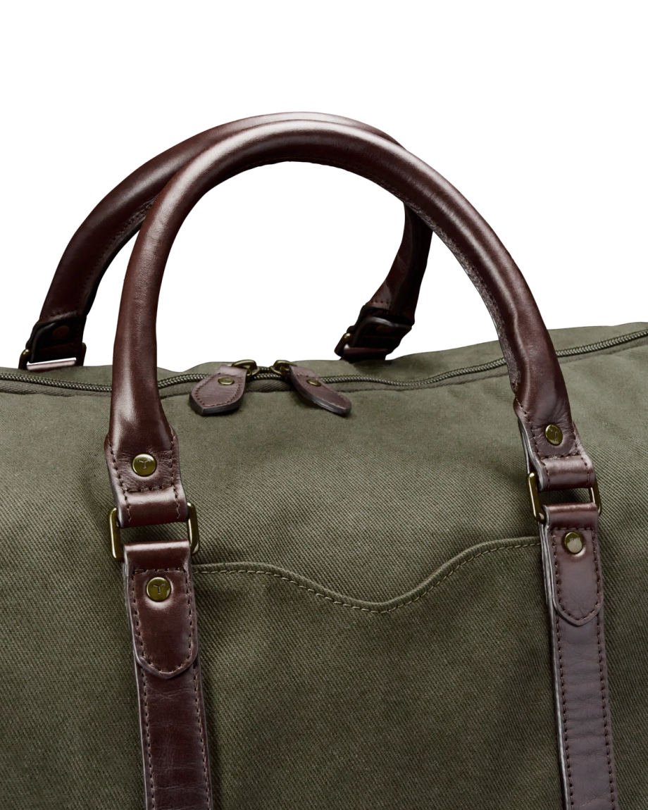 A green canvas duffel bag with brown leather handles and straps, shown against a black background.