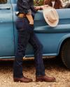 Man wearing jeans and holding hate near a blue truck