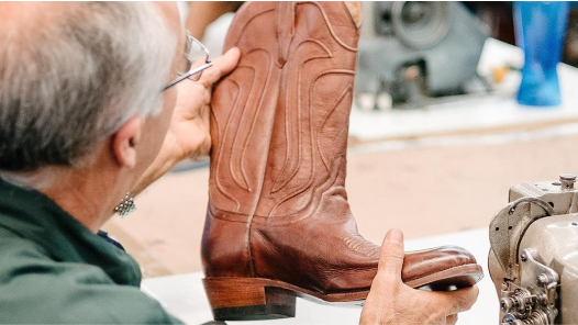 A man is working on a pair of cowboy boots.