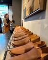 Row of identical brown shoes on display with a person in the background.
