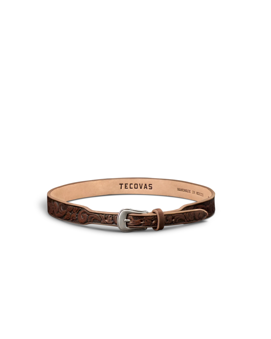 A brown leather belt with floral embossing, a silver buckle, and "Tecovas" branding on the inside. The belt is laid in a circular shape on a white background.
