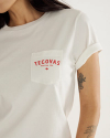 A person wearing a white t-shirt with a front pocket printed with the red text "Tecovas Austin, Tex." and a small graphic; a floral tattoo is visible on the arm.