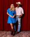Couple standing behind stage wearing western apparel and boots