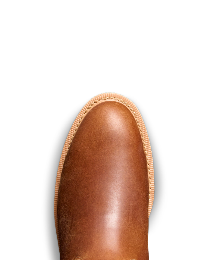 Close-up of a brown leather shoe's toe with stitching detail against a solid black background.