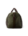 Green canvas duffel bag with brown leather accents and handles, standing upright against a black background.