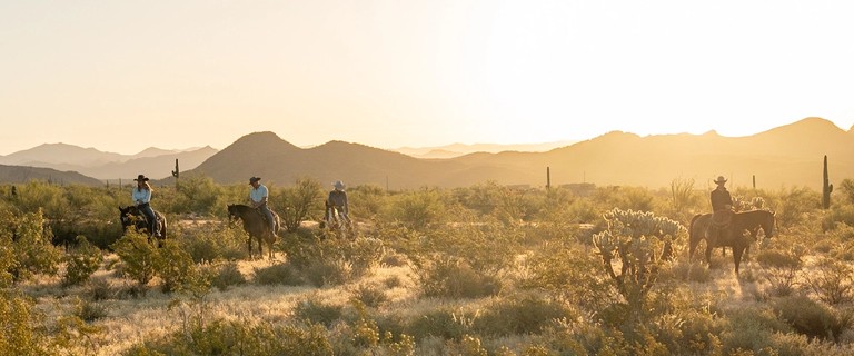 men and women on horses in the desert