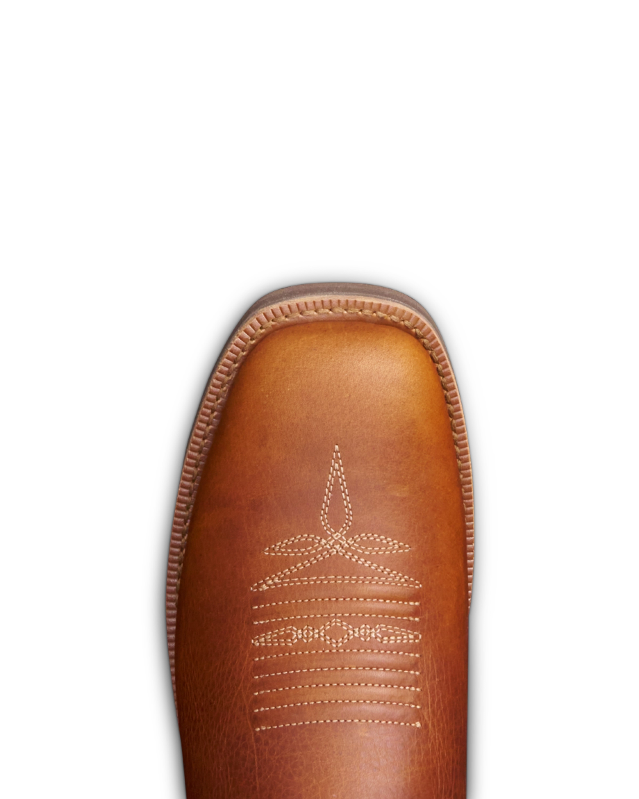 Brown leather cowboy boot with white stitched decorative pattern on the toe, against a black background.