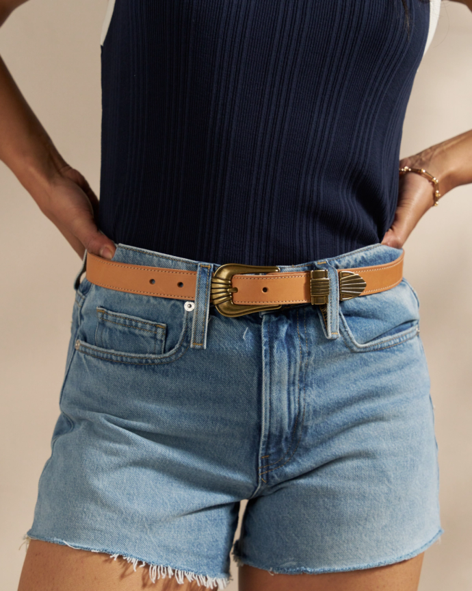 Closeup of woman wearing the art deco belt in tan with denim shorts in a studio