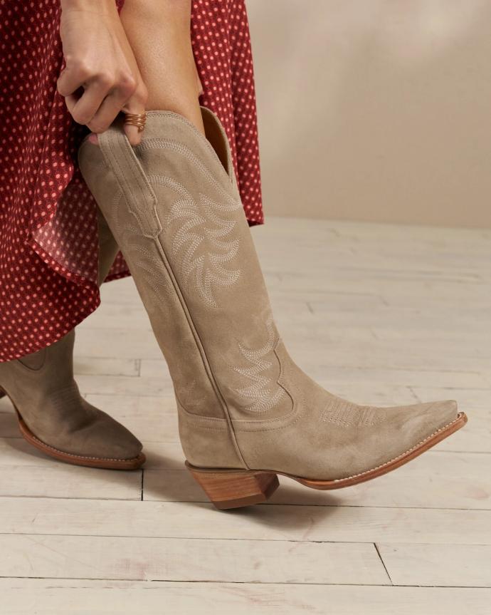 Closeup of woman putting on tan boots in a photo studio