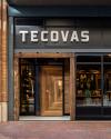 Storefront of tecovas with a wooden door and visible interior, featuring shelves of merchandise under warm lighting.