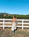 Woman wearing Blue boots standing by a fence