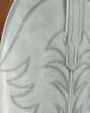Close-up of light gray leather with decorative stitching, showing part of a boot shaft and pull strap.