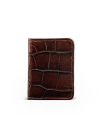 A closed brown leather wallet with a crocodile skin pattern, standing upright against a plain white background.
