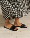 Closeup of woman wearing black sandals with a gingham dress