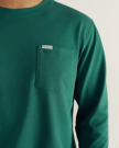 Person wearing a green long-sleeve shirt with a chest pocket and a “Tecovas” label above the pocket.