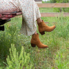 Woman in suede booties sitting on the tailgate of an old pickup truck