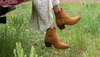 Woman in suede booties sitting on the tailgate of an old pickup truck