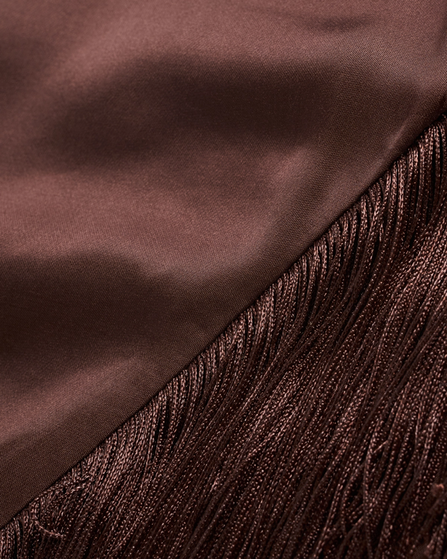 Close-up of a brown satin fabric meeting a section of matching brown fringe, showing the different textures and sheen of each material.