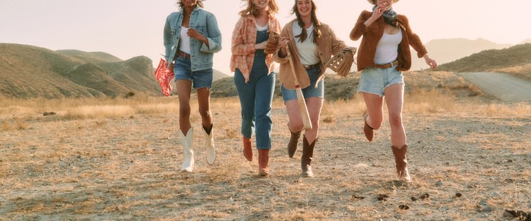 Women wearing tall cowgirl boots, running in the desert