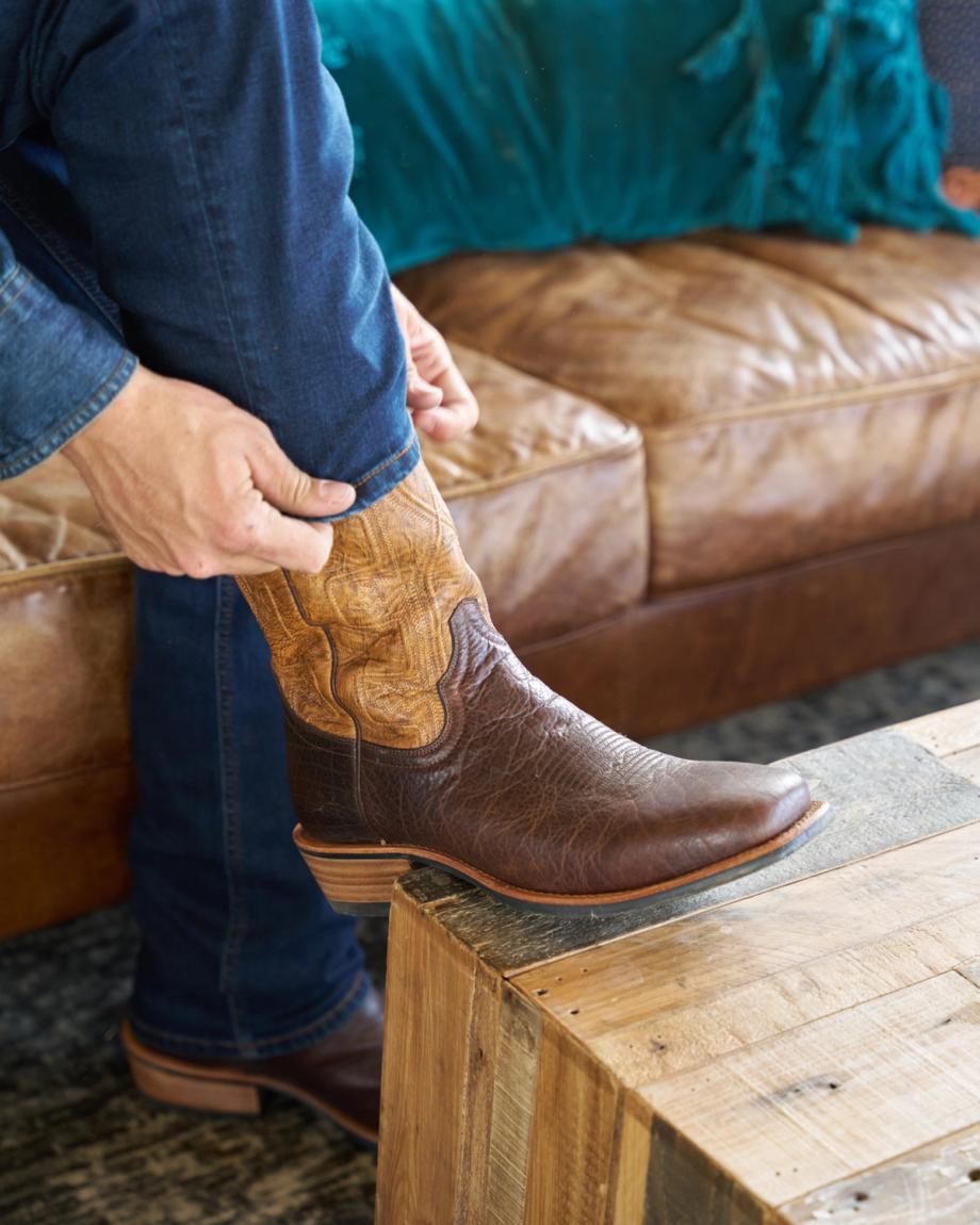 Man putting on the cody in chocolate on a leather couch
