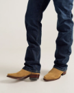 Person wearing blue jeans and tan suede cowboy boots, standing on a light-colored surface.