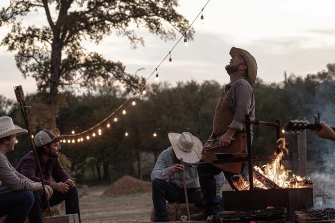 4 men laughing by a bbq pit