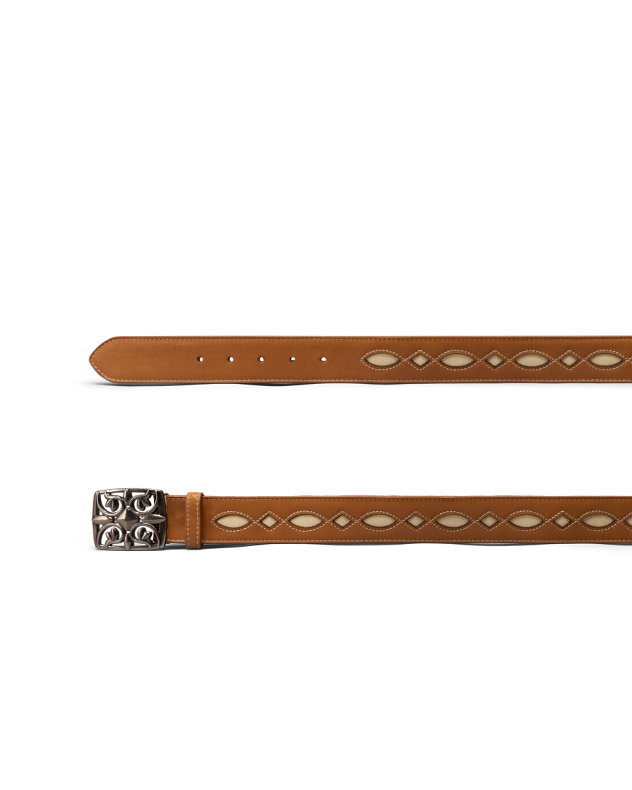 Tan leather belt with white diamond-shaped cutout details and a silver buckle featuring a raised decorative pattern, displayed flat on a white background.