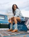 A woman with curly hair sits on the bed of a truck, wearing a light blue shirt, denim shorts, and cowboy boots. Text reads "The Jamie" and "Better Than Ever.