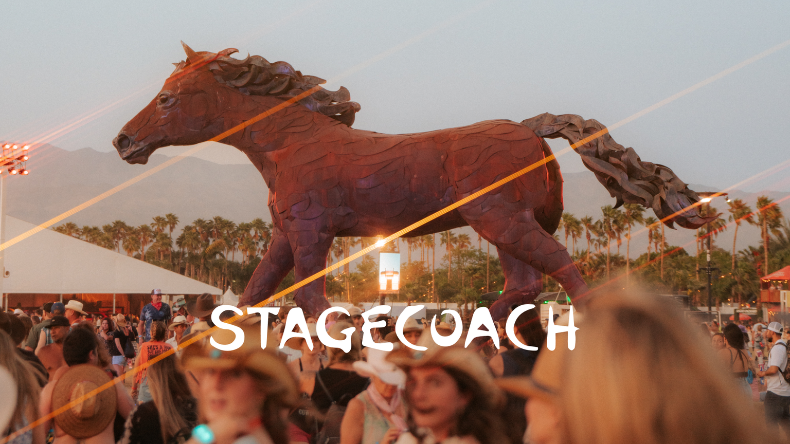 Large metal horse sculpture at a crowded outdoor music festival with the word "stagecoach" overlaid at sunset.
