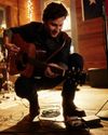 Man leaning down on stage with a guitar