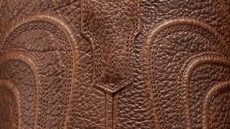 Close-up of brown textured leather with decorative stitching patterns.