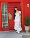 Woman in long dress and white boots in front of red door