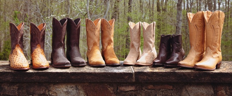 Men and women in cowboy and cowgirl boots standing in a row.