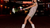 Woman dancing in sequin dress, white cowgirl boots, and a hat