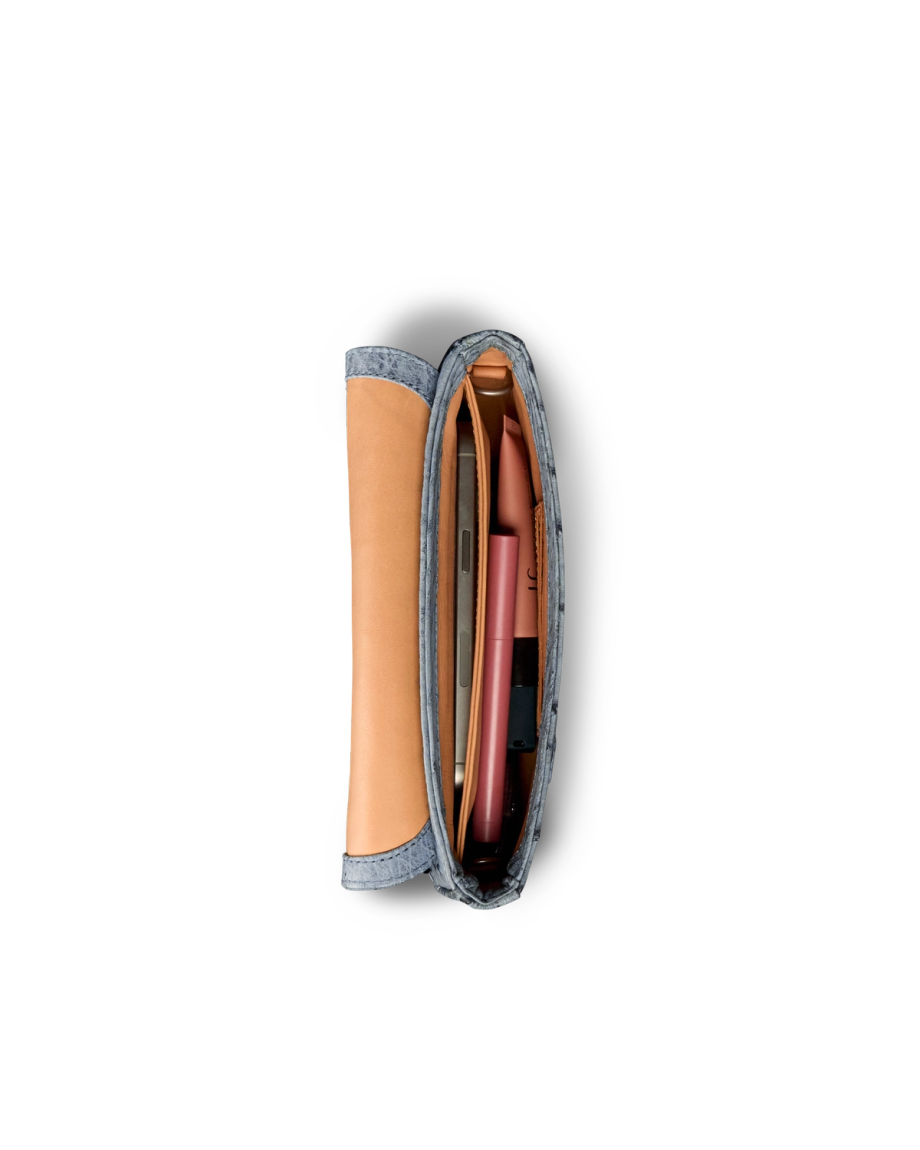 Top view of an open, slim pouch containing a brown notebook, a pink pen, and other small items, all organized neatly inside.