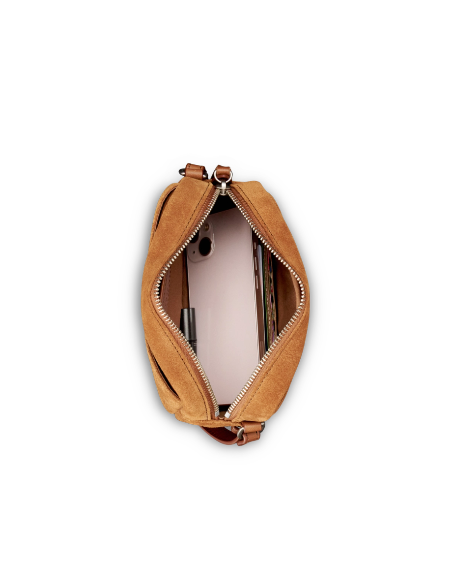 A brown suede purse with a zipper is open, revealing a smartphone, some cards, and a pen inside against a black background.