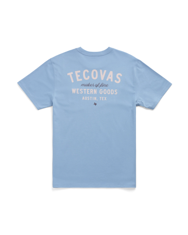 Light blue short-sleeve t-shirt with “Tecovas maker of fine Western Goods Austin, Tex” printed in white and beige text on the back.
