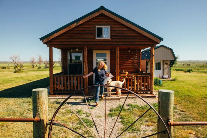 woman coming out of her log cabin