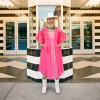 Woman in a pink dress and white hat wearing white cowgirl boots