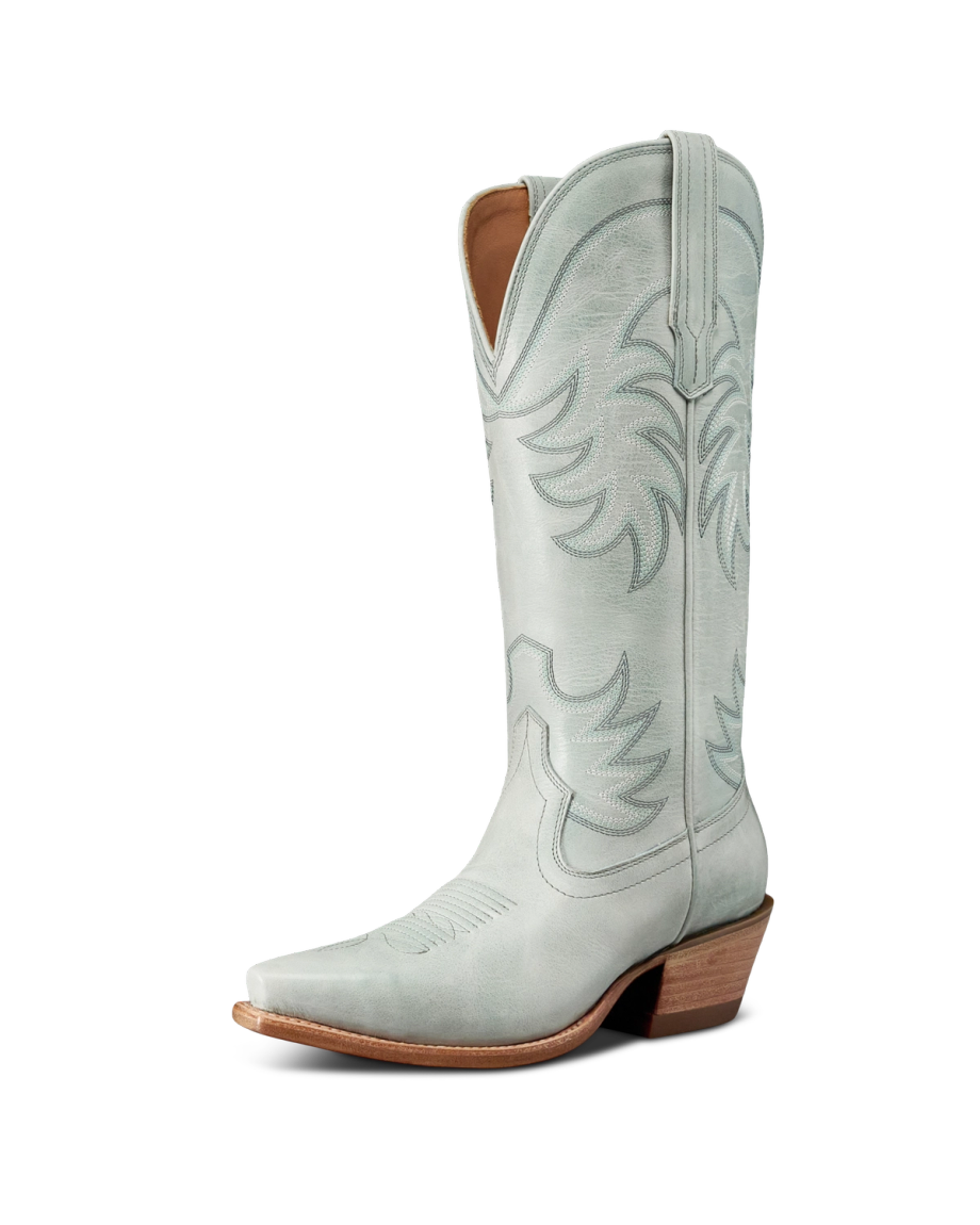 The Annie in Slate Blue Cowhide. Light gray, tall cowboy boot with decorative stitching, a pointed toe, angled heel, and side pull tabs, photographed on a white background.