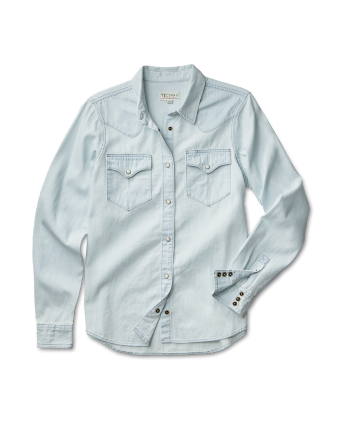 Light blue denim shirt with button-up front and two chest pockets, laid flat on a solid black background.