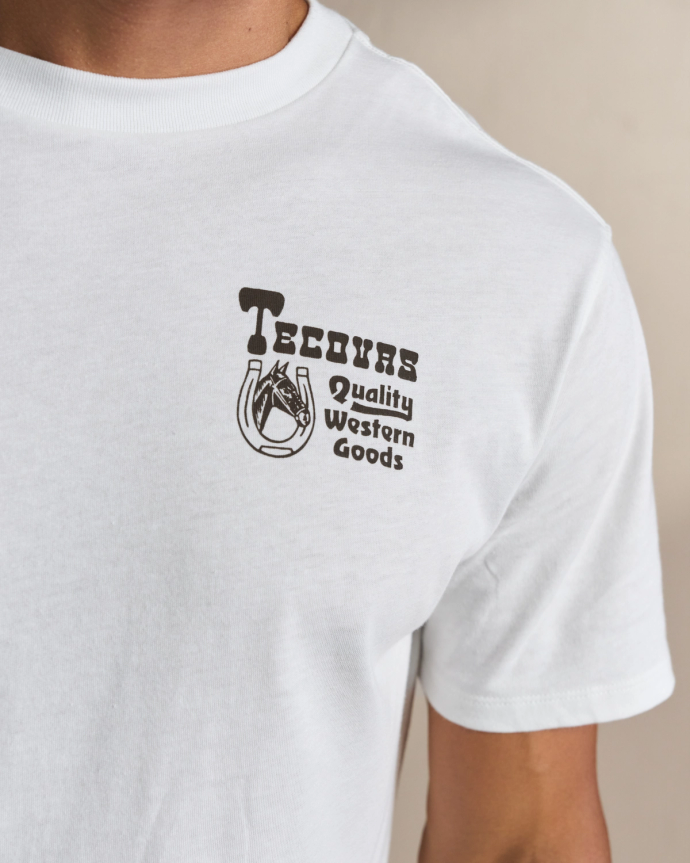 A person wearing a white t-shirt with the text "Tecovas Quality Western Goods" and a horse illustration on the left chest.