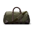 A large green duffel bag with brown leather accents and a shoulder strap.