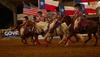 People riding horses with flags at a rodeo
