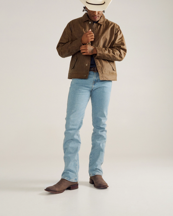 Person wearing a brown jacket, light blue jeans, brown cowboy boots, and a white cowboy hat against a plain background. Face is partially obscured by the hat.