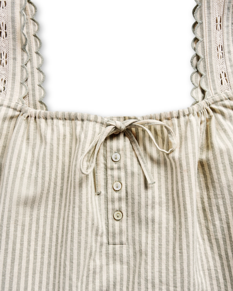 Close-up of a sleeveless striped top with lace-trimmed straps, three buttons, and a drawstring at the neckline, set against a black background.