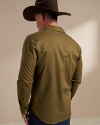 A person wearing a brown cowboy hat and green long-sleeve shirt stands facing away in a neutral indoor setting.