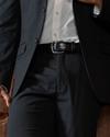 Close up of a man's waist who is wearing a suit and midnight colored crocodile belt