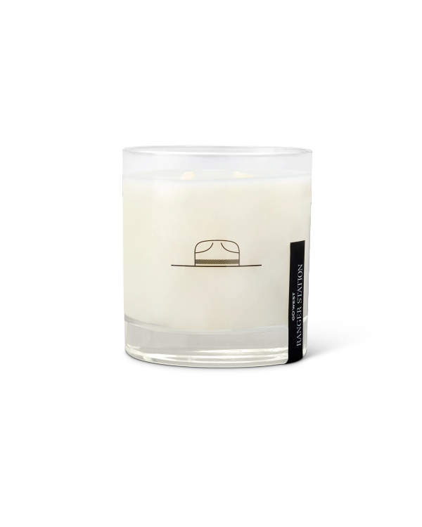 A glass jar candle with a minimalistic design, featuring a small illustration of a hat on the front.